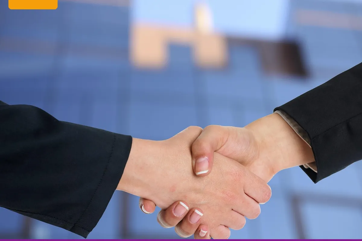 Two people shaking hands in front of an office building