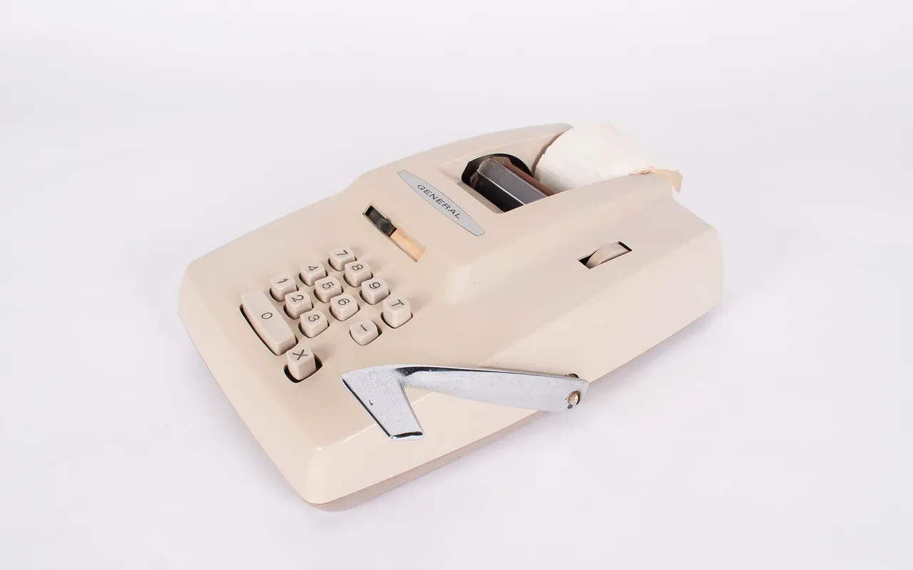 An adding machine with a paper tape, on a plain white ground.