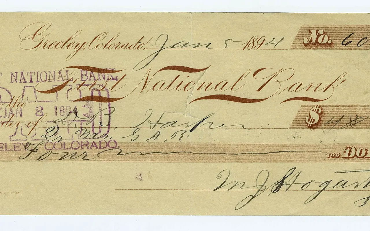 A cancelled bank check with a paid stamp and the amount written in words.
