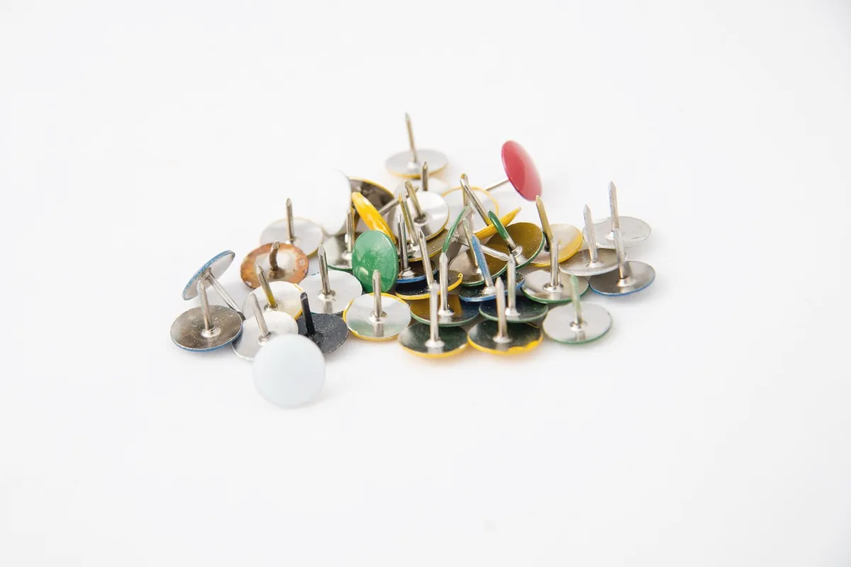 A scatter of push pins on a white ground, with no writing.