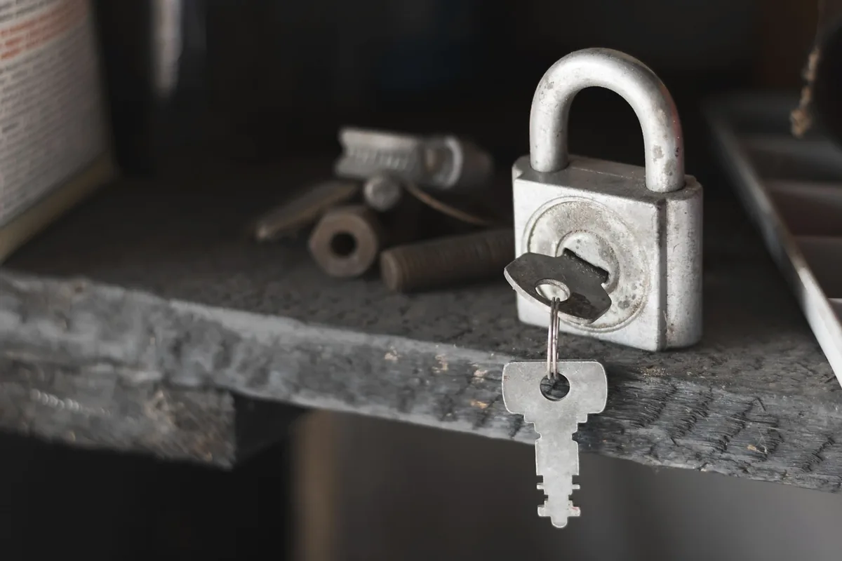 A padlock and two keys on a rough ledge, with no tag.