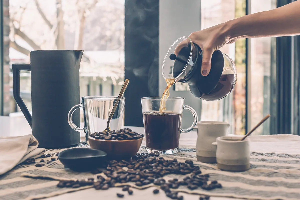 Coffee being poured into a dark mug, with no logo on the cup.