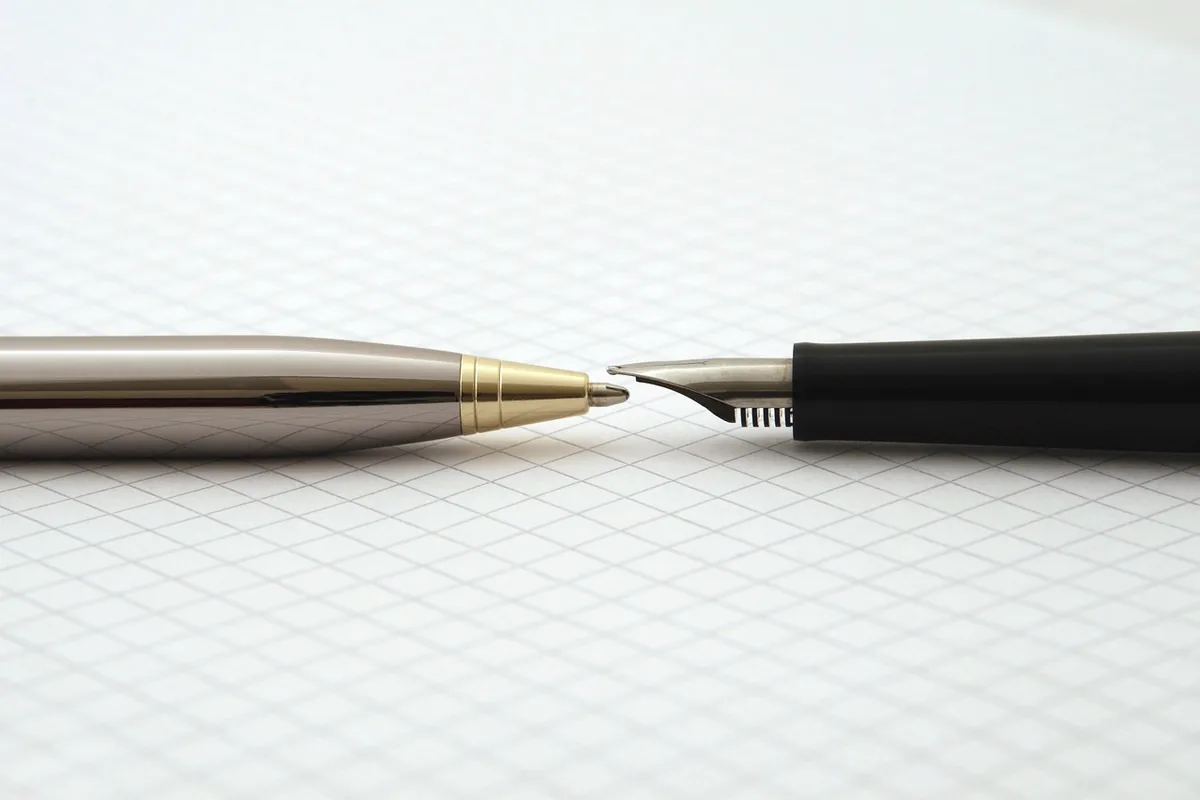 Two pens on blank graph paper, with no writing.