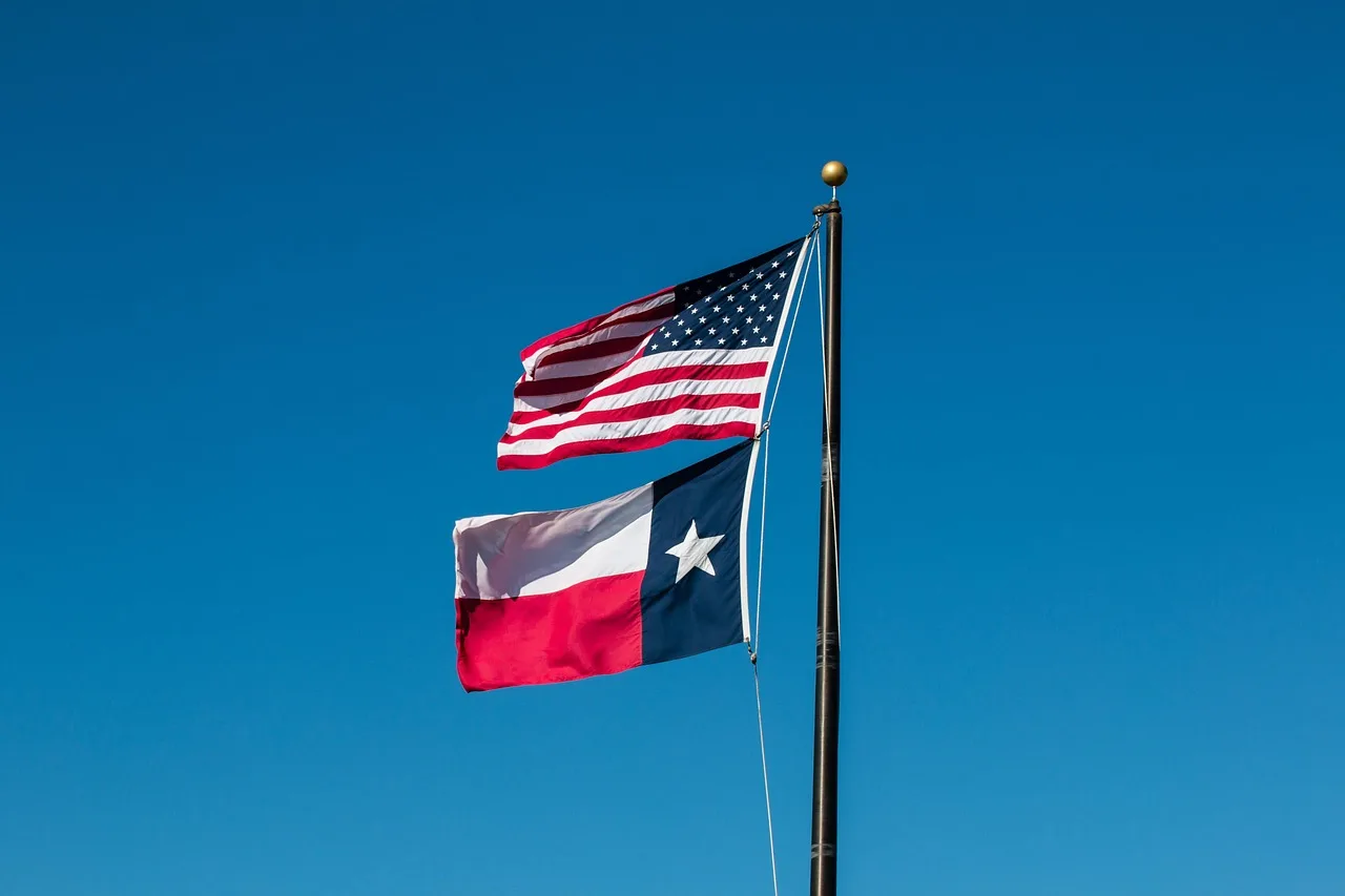 The United States flag flying above the Texas flag on one pole