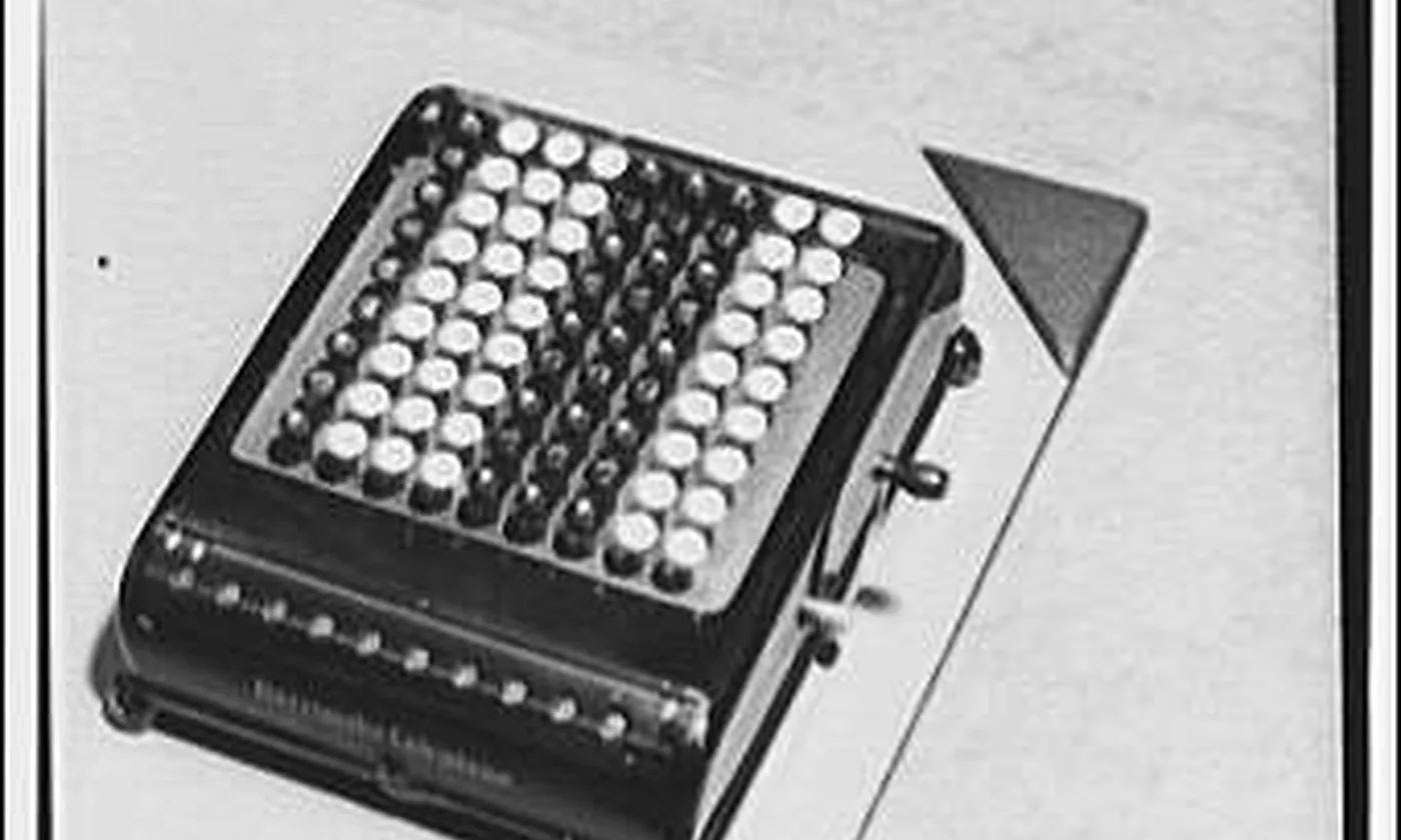 A Burroughs adding machine on a light table, seen from above.