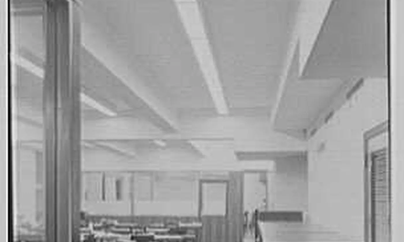 An empty bookkeeping room, with desks, chairs, and a long counter, and no one in the chairs.