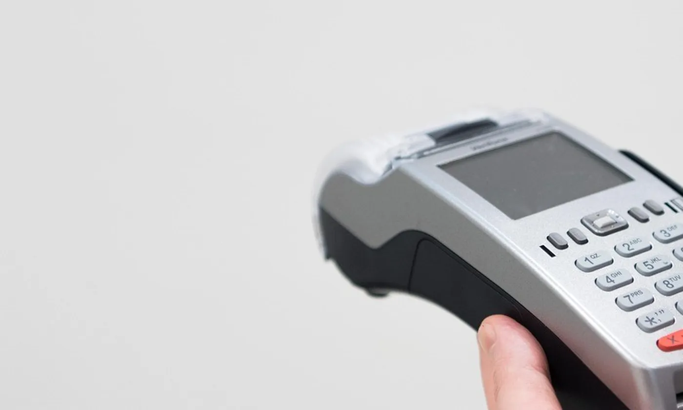 A card terminal in two hands, cropped so the card brand is out of the frame.
