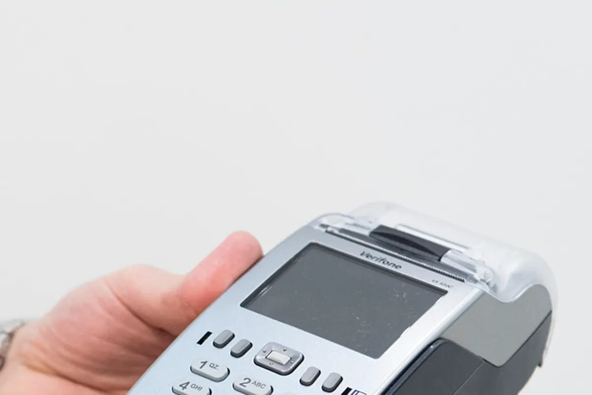 A card terminal in a hand, screen blank, no guest name.