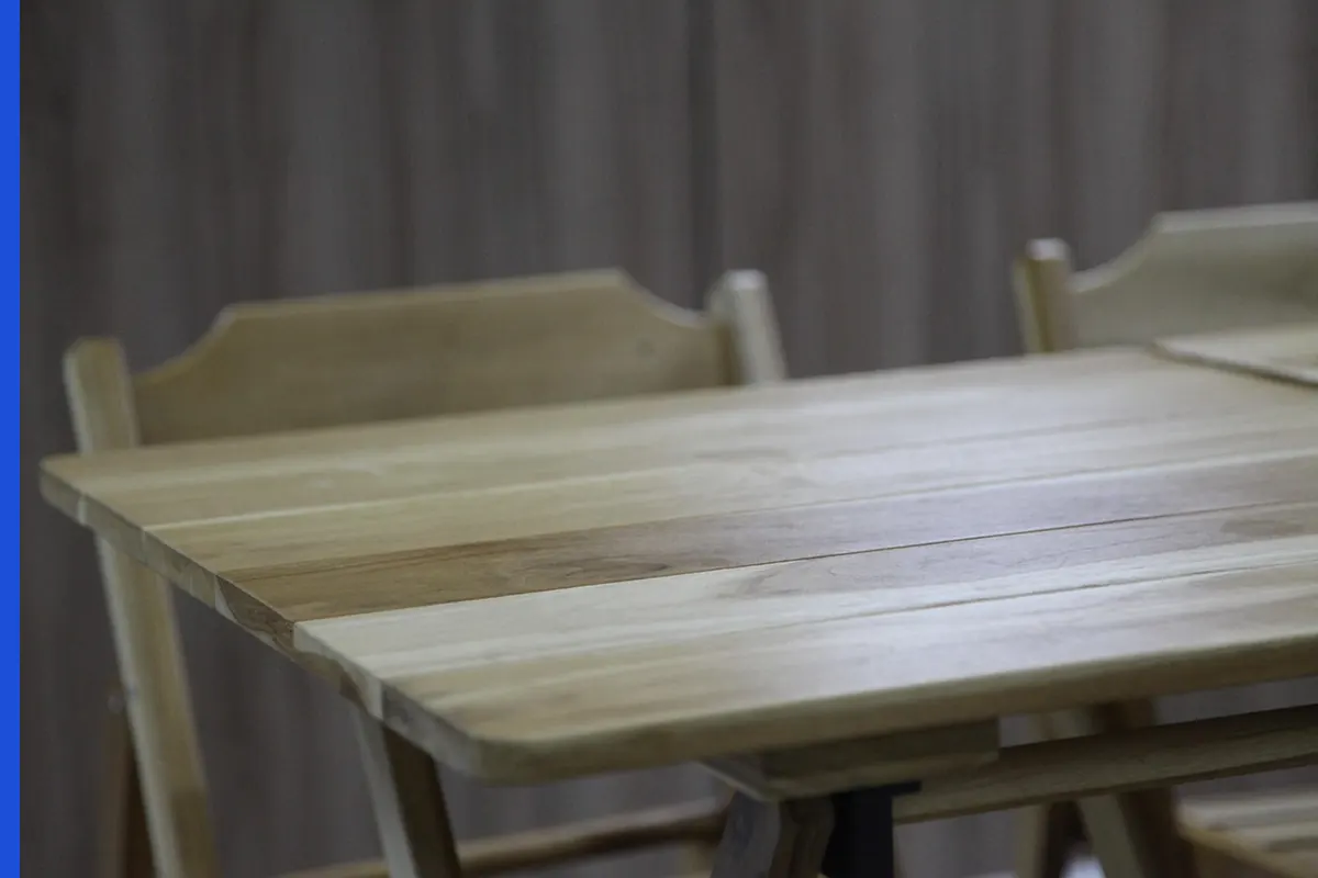 A pale wood table with empty chairs and no writing.