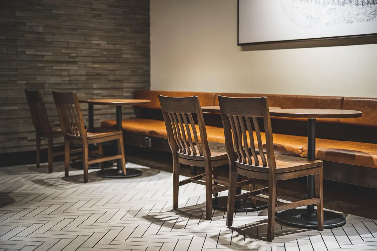 An empty dining room after close, wooden chairs and a leather booth, no guests.