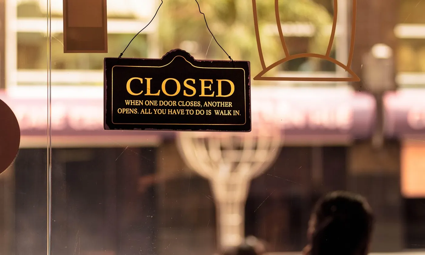 A closed sign hanging in a shop door after the day is done.