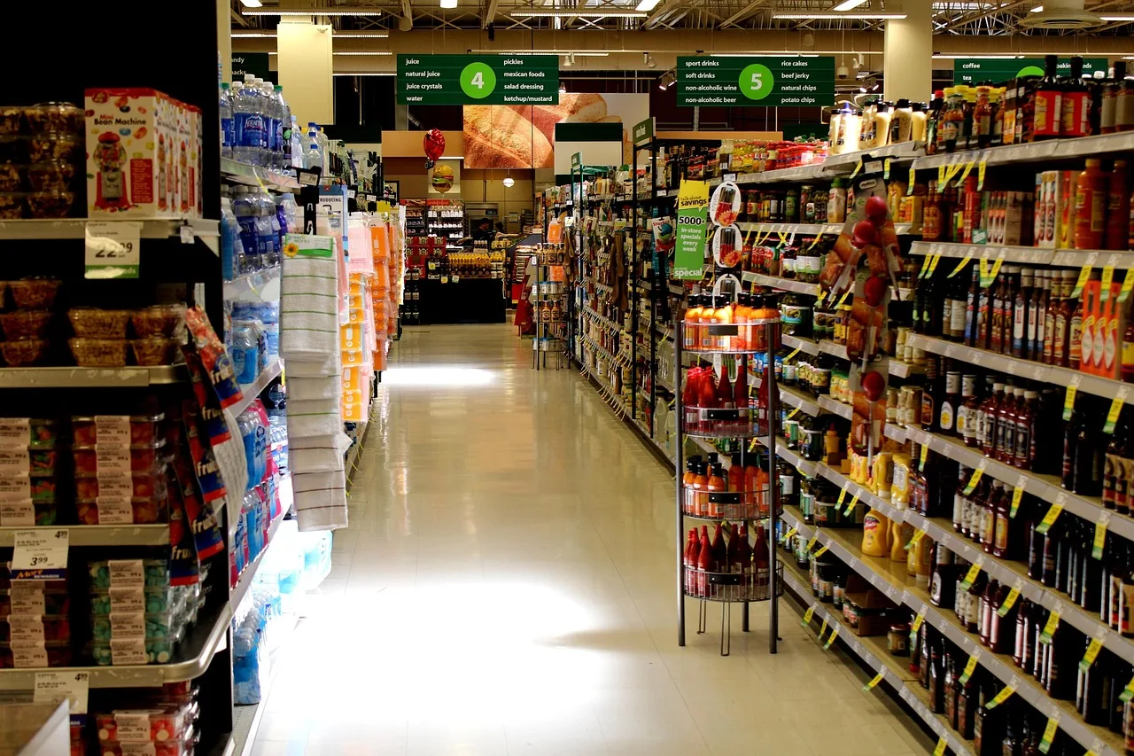 A wide supermarket aisle with stocked shelves, the walk-in side of a store.