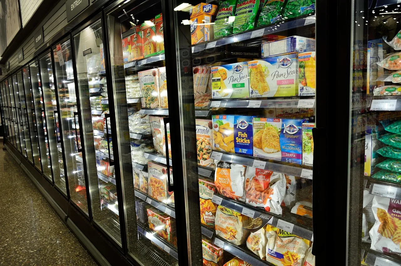 A grocery freezer aisle of packaged meals, goods whose cost belongs in the month they sell.