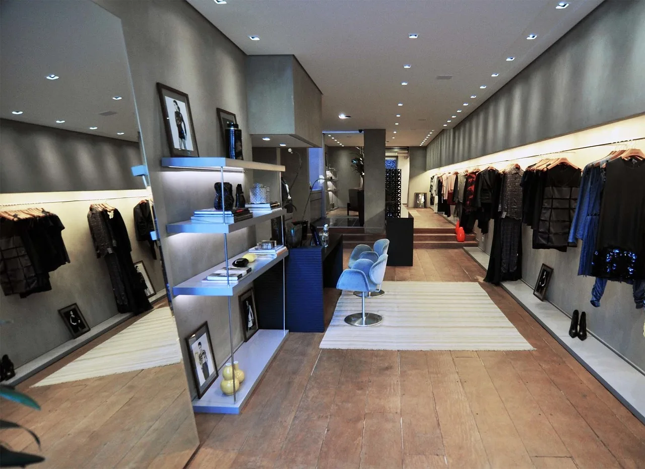 An empty clothing shop after hours, racks still full and the lights left on.