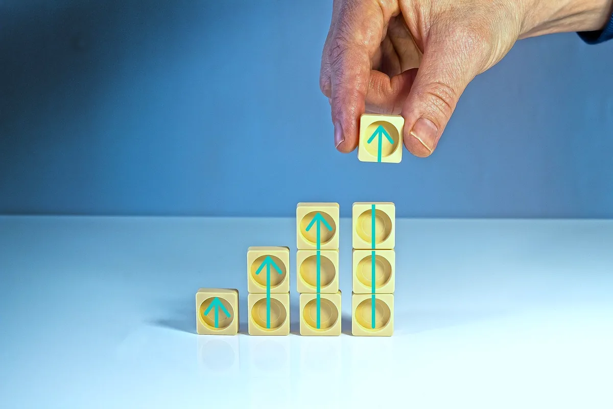 Two stacks of blank blocks, one taller, with a hand adding a block.