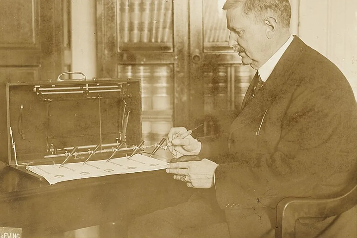 A man at a table operating a Treasury machine that writes checks, Harris and Ewing photograph.