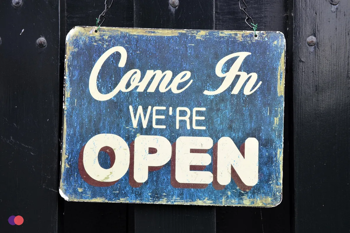 A hand-painted sign on a shop door that says come in, we are open