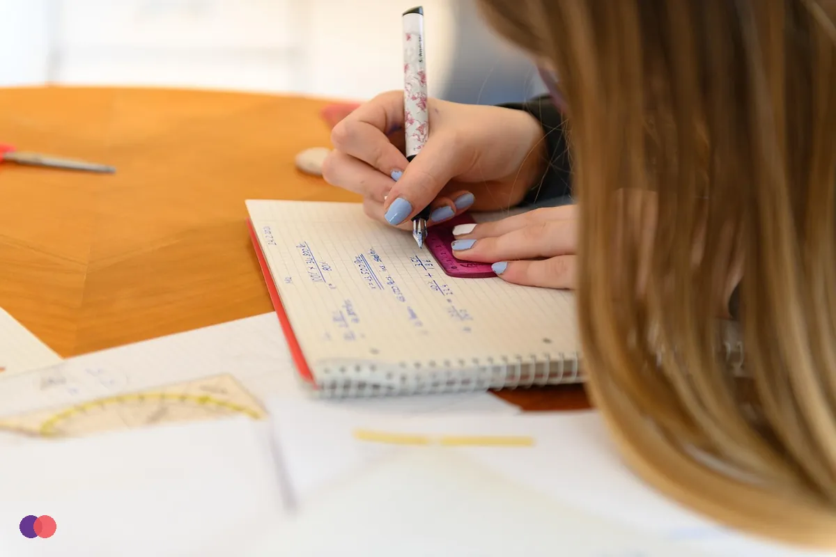 A hand filling in a page with a pen at a table
