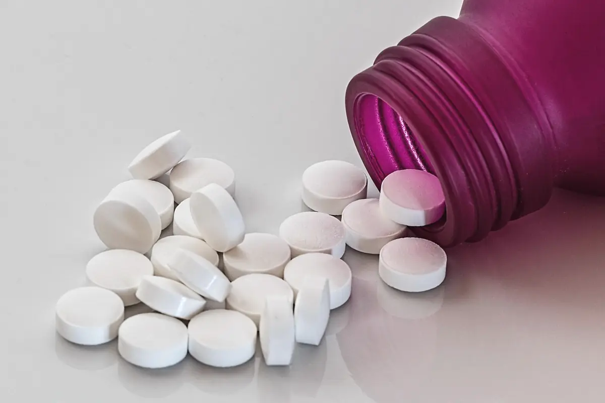Loose white tablets beside a plain bottle with no label