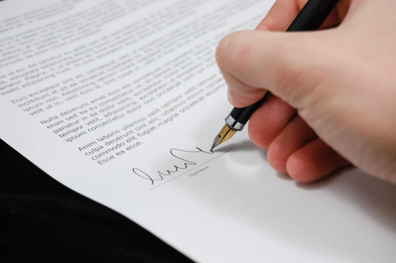 A hand signing a printed page