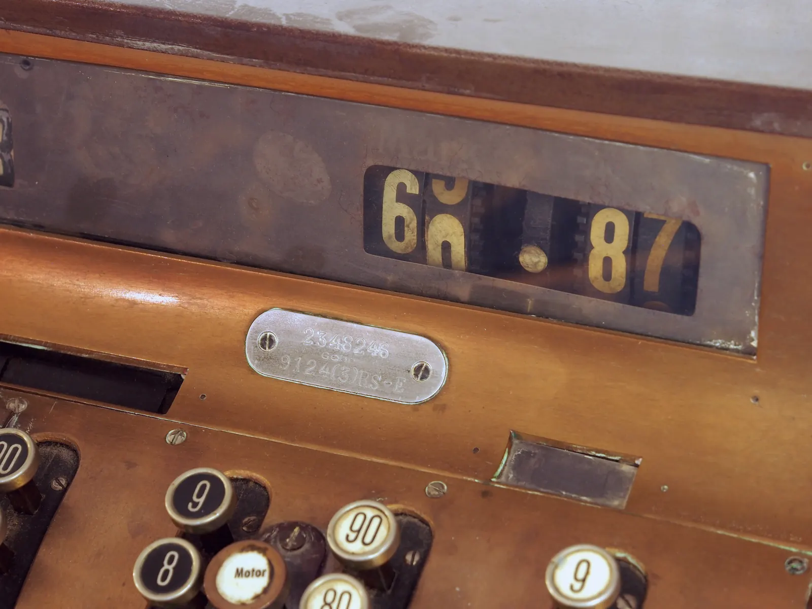 The window of an old cash register shows a total, with number keys along the front.