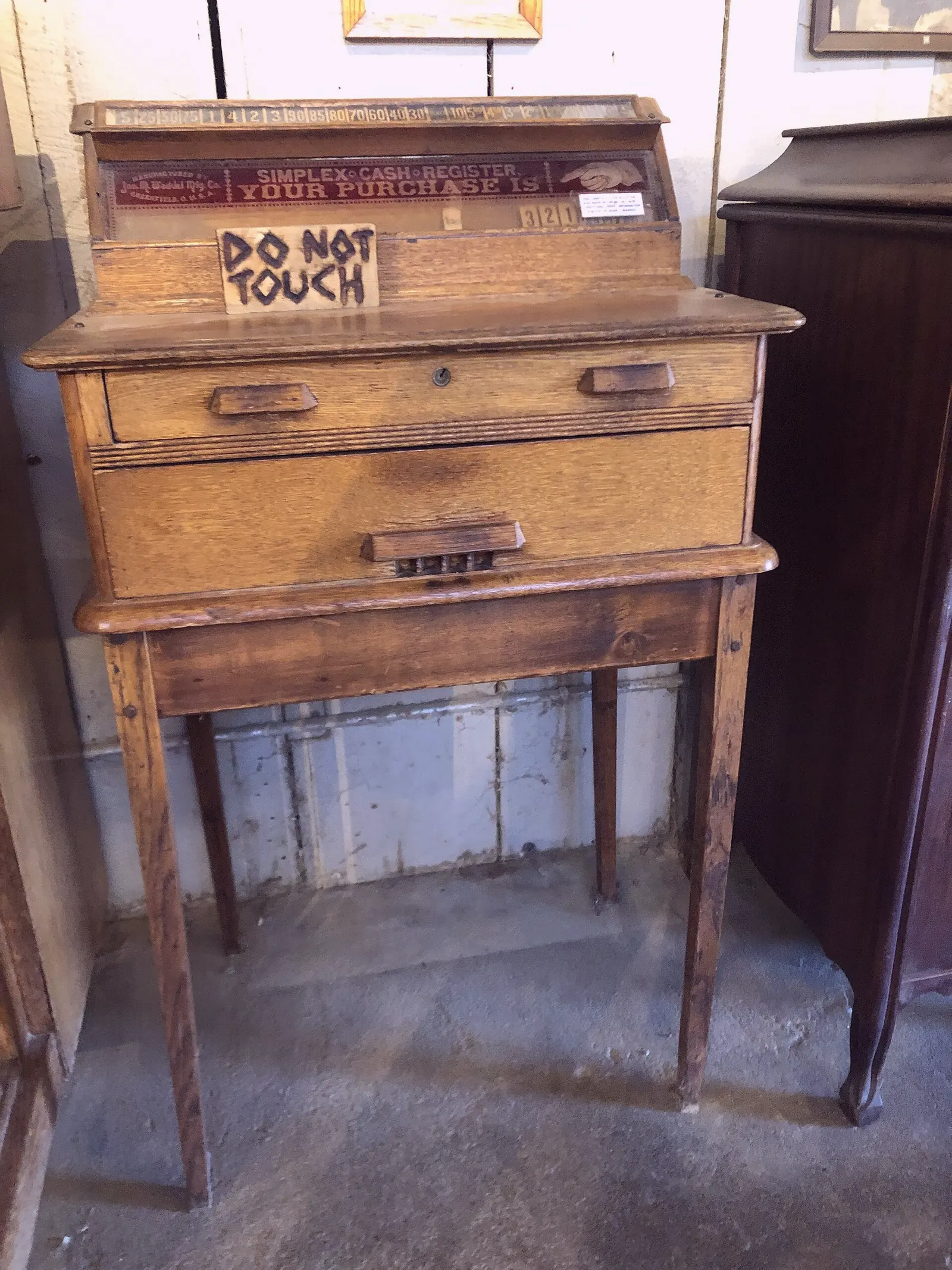 A wooden Simplex cash register with a closed drawer and a small purchase window.
